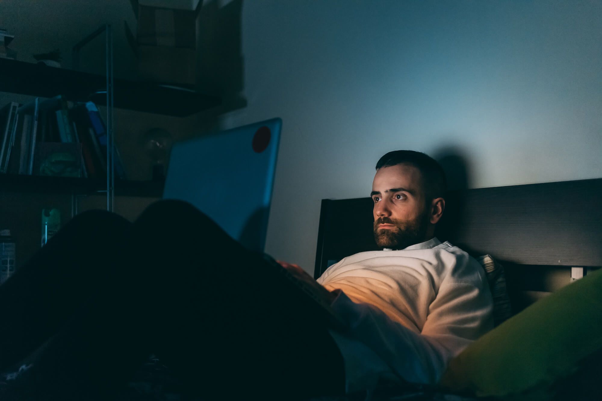 A man in moody room holding his laptop 
