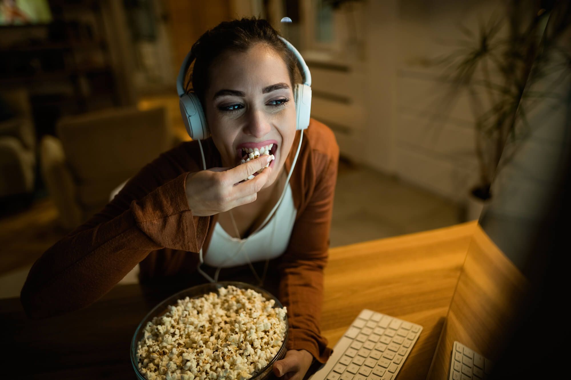 A young woman with headphones eating popcorn