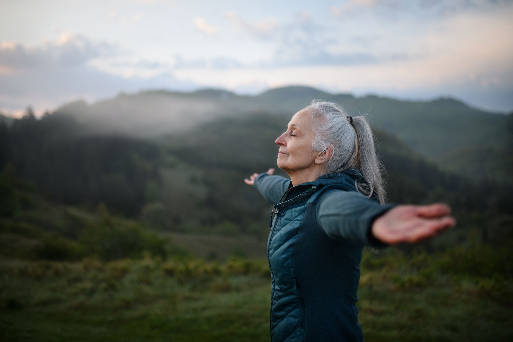 A senior woman taking deep breaths in nature, enjoying life