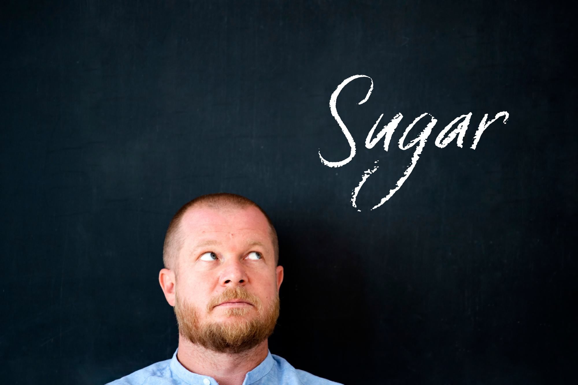 A man staring at sugar sign writen with chalk