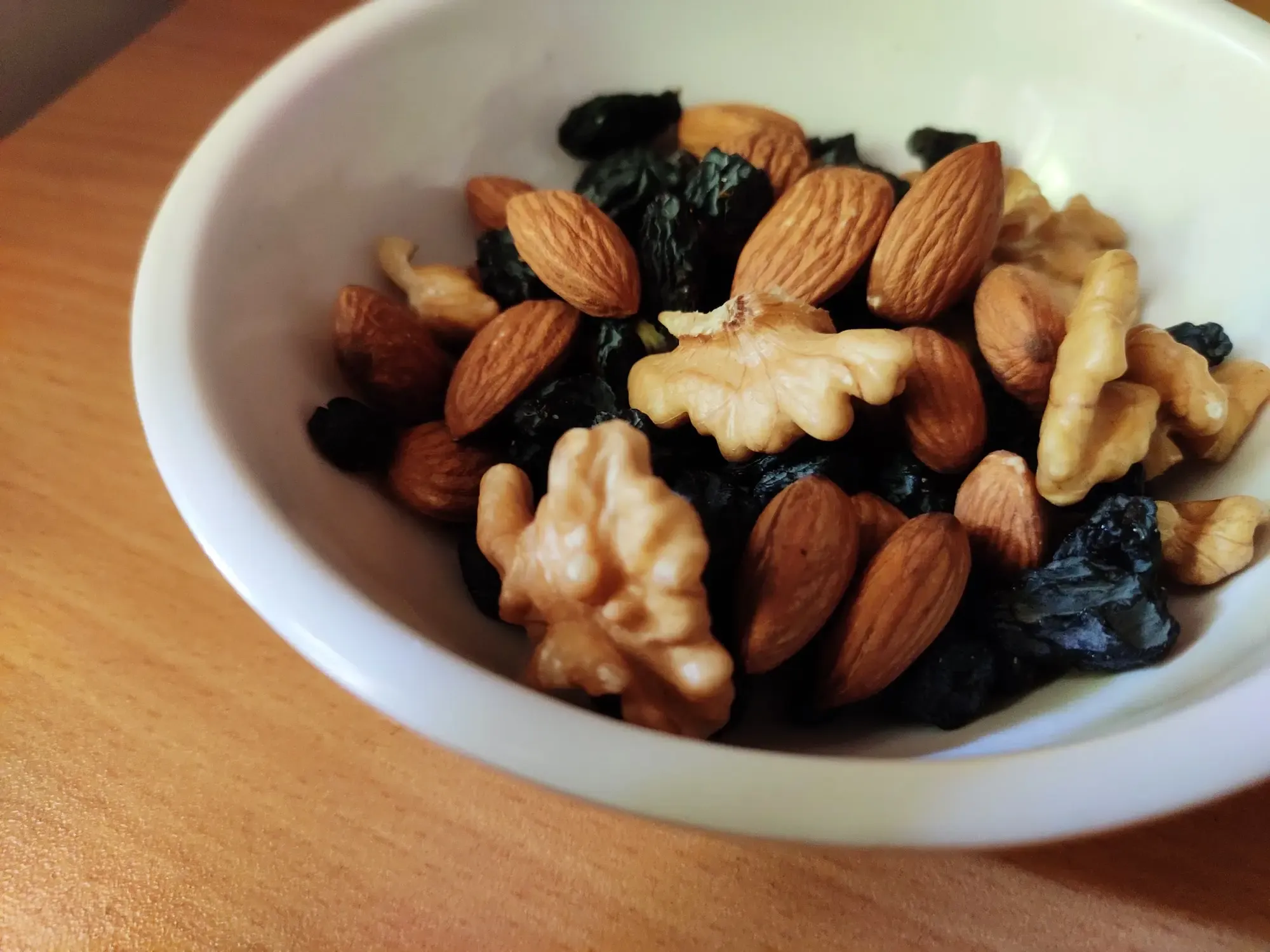 cashew, dried fruit, and almonds in a small white bowl