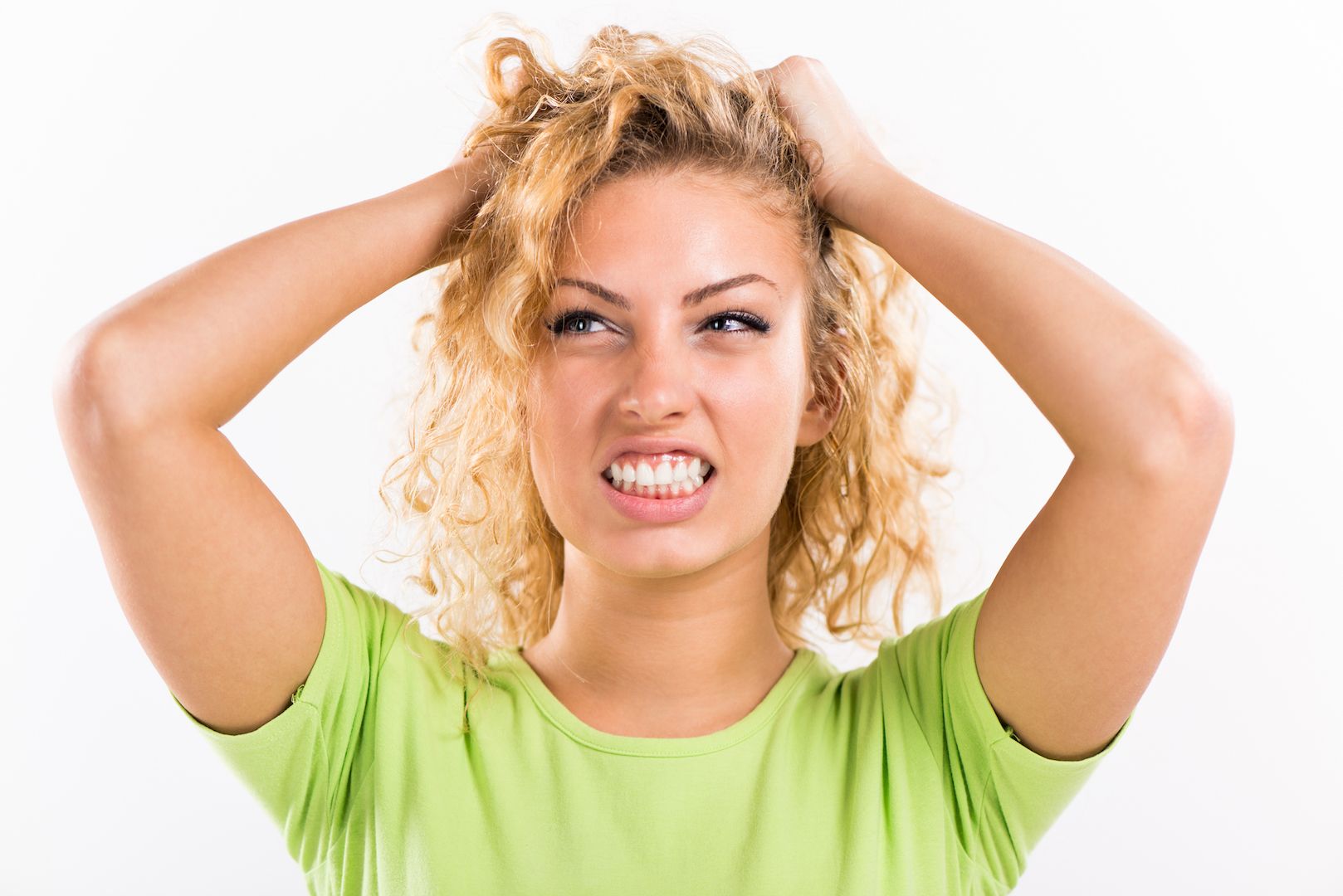 A blond woman grimmasing, pulling her hair due to stress
