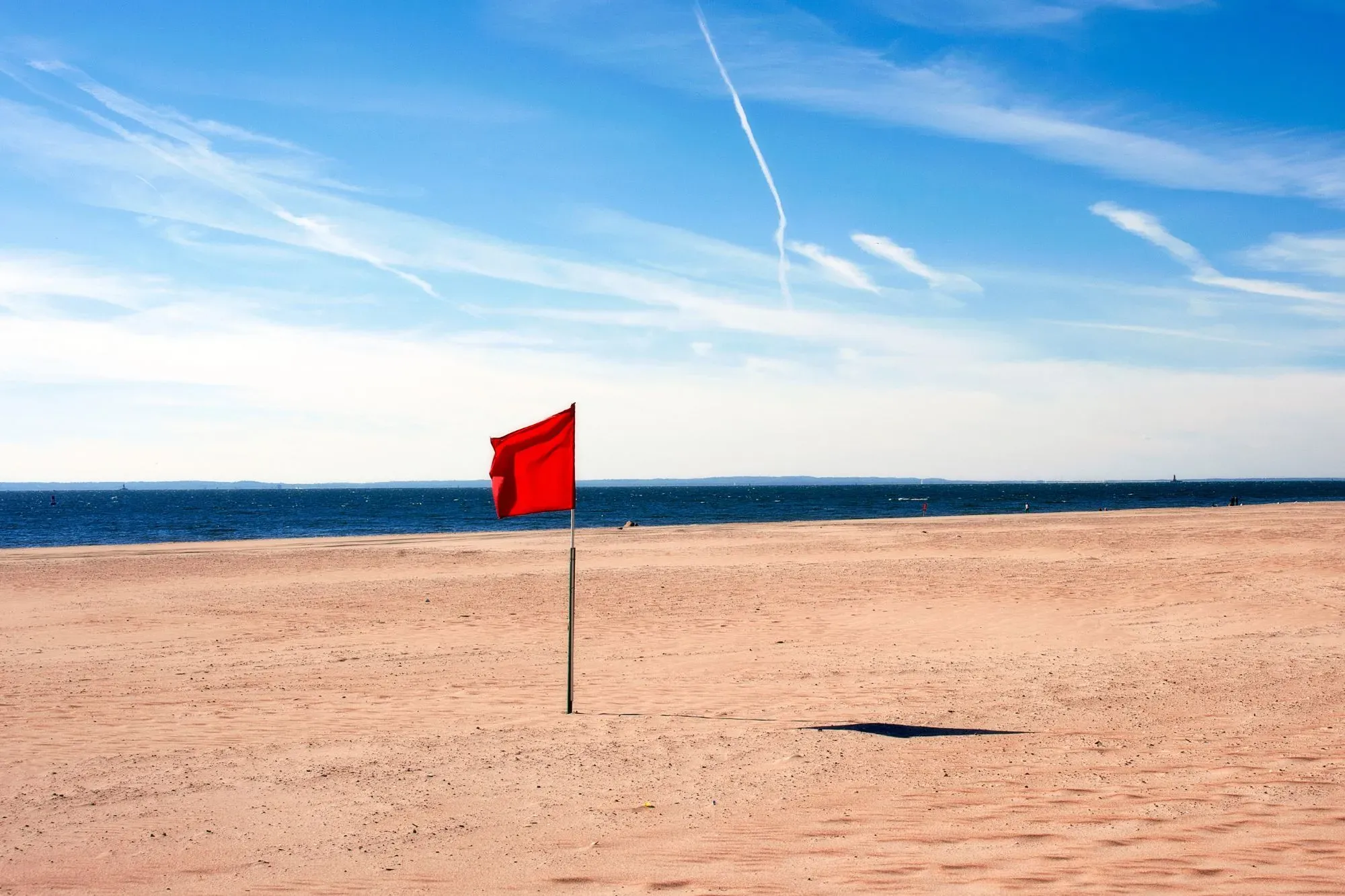 A red flag on the beach giving a warning sign