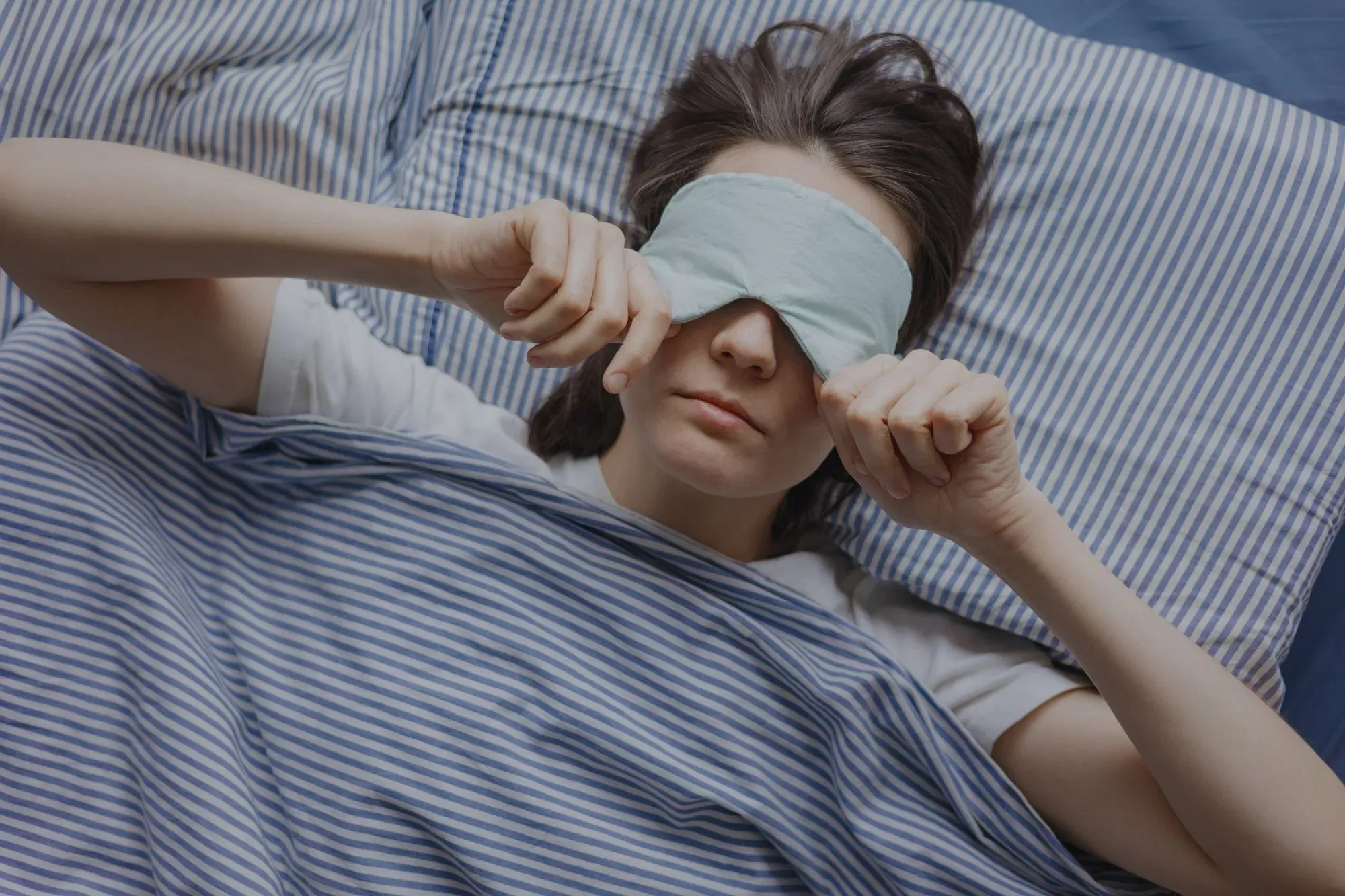 A woman covering her eyes before sleep after a light workout before bed