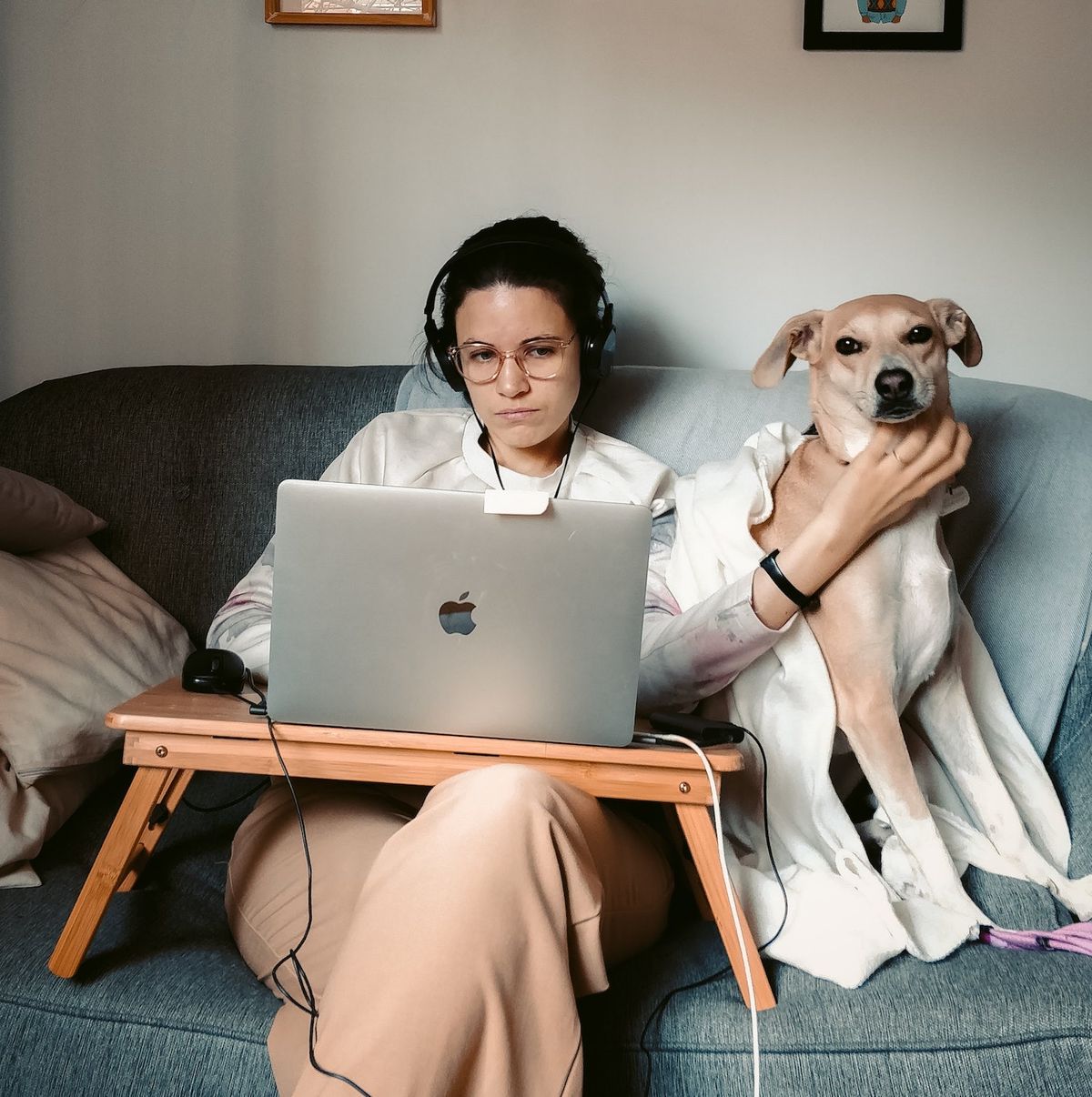 A woman cuddling her dog while working in her couch