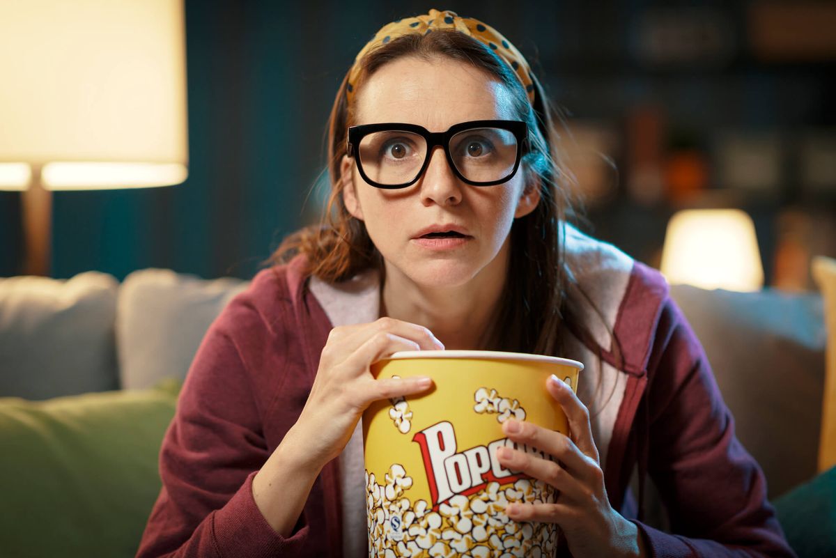 A woman binge watching her favorite show, eating popcorns