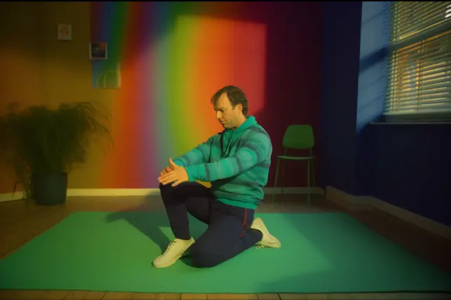 A man in his colorful room doing lower back stretches to release tension