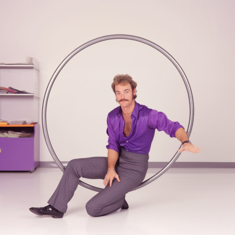 A guy in tight clothes sitting in a circle showing a trick