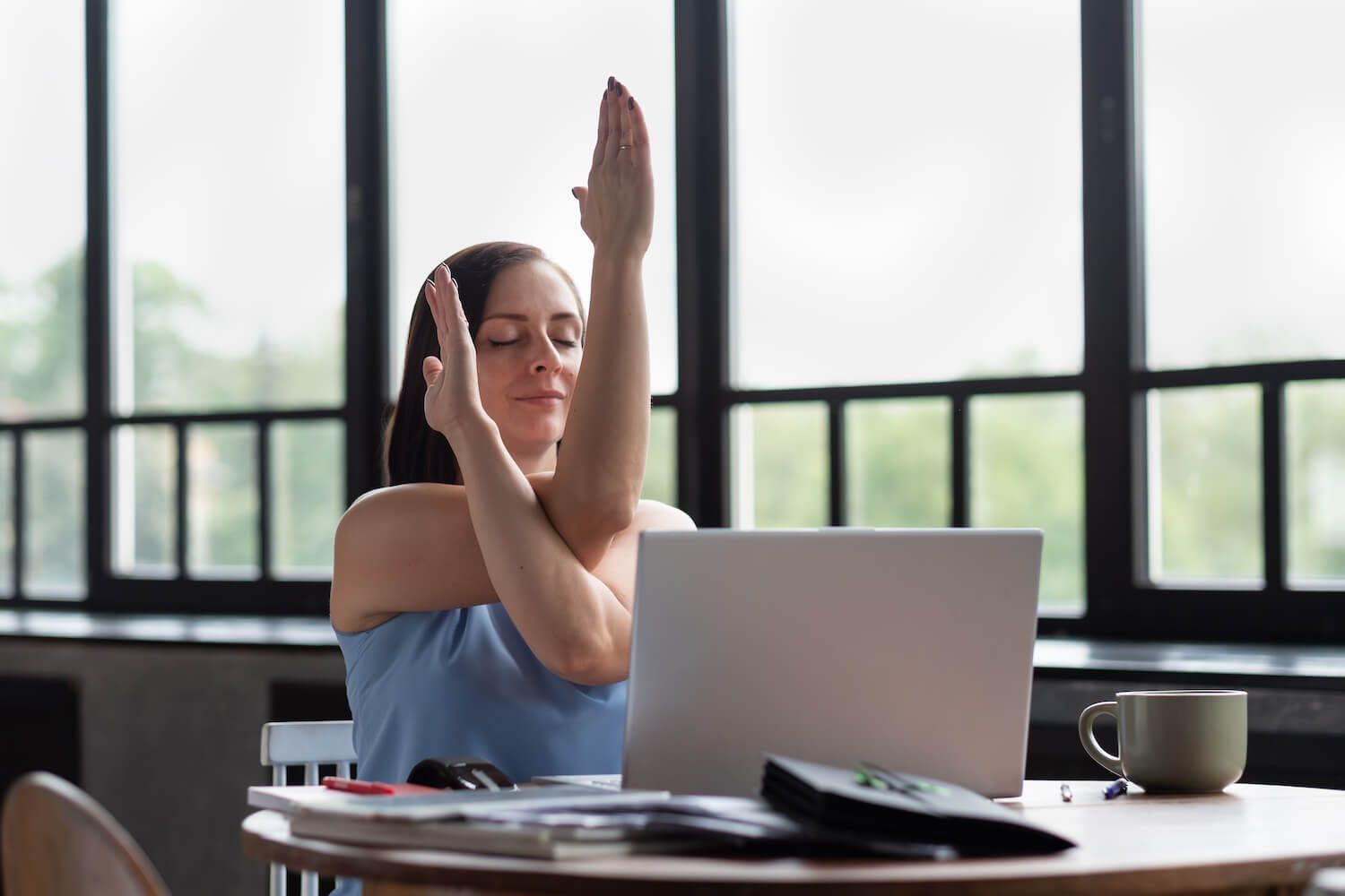 A woman doing light yoga by her laptop